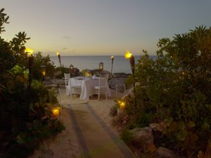romantisches dinner am strand mit kerzen und fackeln im luxuriösen modernen designer hotel und resort auf den turks- und caicosinseln in der karibik  auf dem sand am meer mit teppich